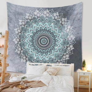 Détail d'une tapisserie mandala bohème grise et bleue suspendue au-dessus d'un lit
