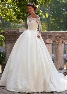 Detail of elegant off-shoulder lace long sleeves and satin bodice on white bridal gown