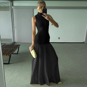 Dettaglio dell'elegante top nero in maglia abbinato a una gonna lunga plissettata