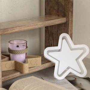 Stervormige siliconen mal voor DIY kandelaars geplaatst op een rustieke houten plank