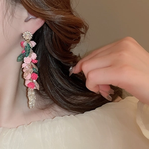 Pink and white acrylic flower drop earrings with crystal tassels shown on a model