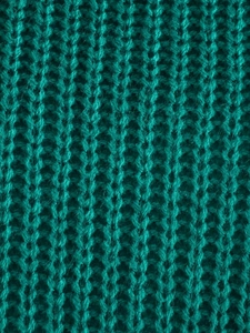 Dettaglio macro del tessuto a maglia grossa verde petrolio con trama a costine