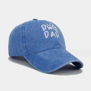 Detailed view of white DOG DAD embroidery on a washed blue denim baseball cap