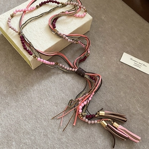 Detail of bohemian multilayer acrylic bead necklace with tassel and golden weave chain