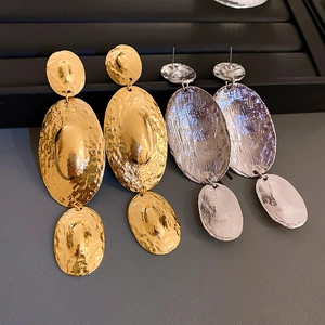 Detail of chunky gold and silver geometric earrings with hammered metal texture