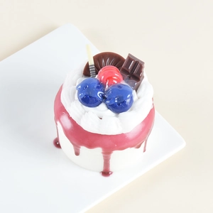 Detailed top view of realistic faux cake model with cream and fruit on a white plate