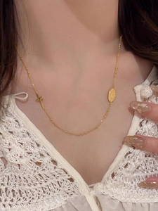 Gros plan des pendentifs croix dorée et médaille ovale sur une chaîne délicate
