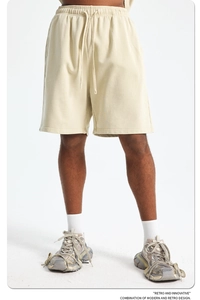 Detail of light beige men's cotton knit shorts showing drawstring waist and thick fabric texture