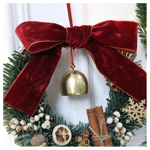 Detailed Christmas wreath featuring a red velvet bow, gold bell, and cinnamon sticks