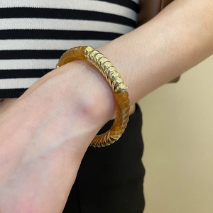 Detail view of acrylic amber and gold spiral segments on a stylish bracelet