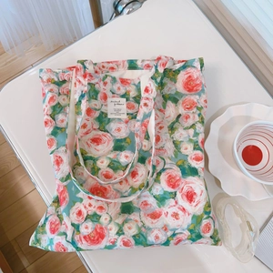 Detail of floral canvas tote bag with pink rose patterns on a white table set