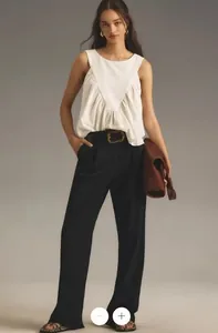 Detail of white sleeveless pleated top with V-shaped stitching and black trousers