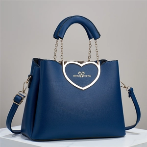 Detailed view of dark blue leather handbag with golden heart-shaped metal buckle and strap