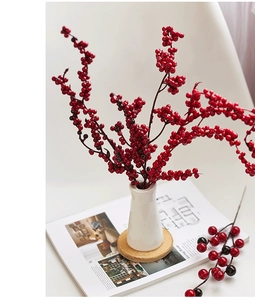 Artificial red berry stems in a white ceramic vase on a wooden base for home decor