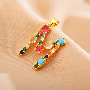 Golden letter M necklace pendant with colorful zirconia crystals on beige fabric
