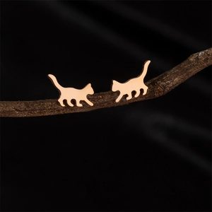 Rose gold walking cat silhouette stud earrings displayed on natural wood branch