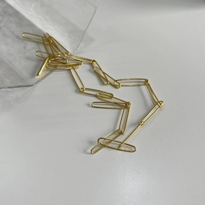 Detailed close-up of golden paperclip chain necklace on a clean white background