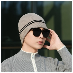 Close-up of khaki winter knit beanie with black stripes and protective ear flaps