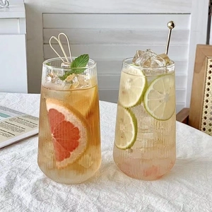 Detailed view of vertical striped glass cups with iced fruit drinks on a white tablecloth