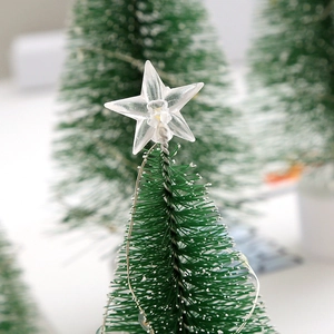 Macro detail of artificial pine needles and glowing star topper on a mini Christmas tree