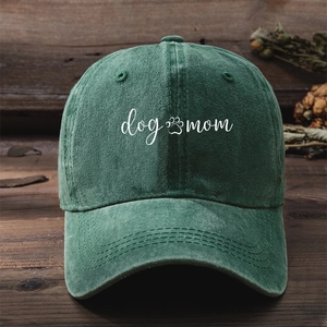 Close-up of 'dog mom' white embroidery on dark green washed cotton baseball cap