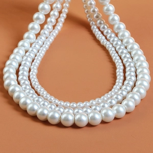Macro shot of layered white pearl necklaces showing gradient sizes and glossy texture