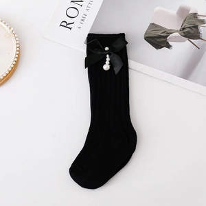 Detail of black ribbed knit socks with large satin bow and hanging pearl pendant