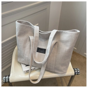 Close-up of oatmeal canvas tote bag on white leather chair with high texture detail