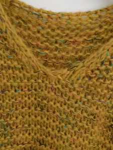 Macro detail of chunky mustard knit texture with vibrant colorful fiber specks