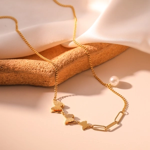 Bohemian gold butterfly and pearl pendant necklace on textured rock with white silk