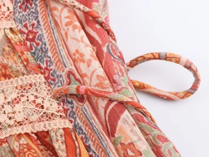 Dettaglio macro della stampa paisley con bordo in pizzo beige e sottile laccetto di chiusura