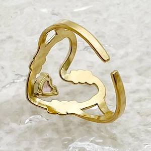 Detail shot of heart-shaped gold-plated stainless steel ring with small pink gemstone