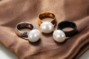 Detailed view of three-color hammered texture rings with large white pearls on silk cloth