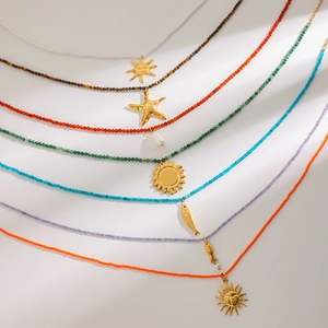 Macro shot of stainless steel beaded necklaces with gold sun and starfish pendants