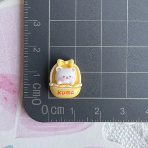 Macro shot of mini resin bear charm in yellow kuma basket showing 1x1cm scale measurement