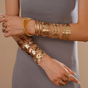 Detail of bohemian gold layered bracelets and butterfly cuff on model arm
