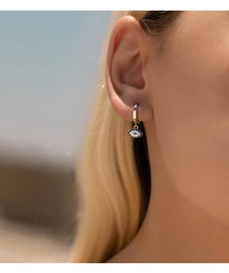 Close-up of S925 silver evil eye hoop earring with blue gems worn by a model