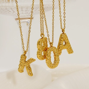 Detail showing gold 26-letter necklaces with unique crinkle texture and polished finish