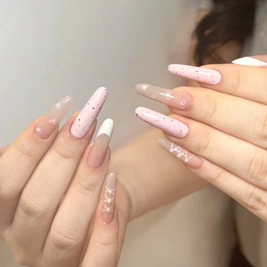 Detail of pink almond nails with white polka dots, ribbon bows and small pearl accents
