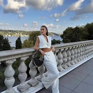 Women's white two-piece set featuring short sleeveless vest and wide leg pants in city view