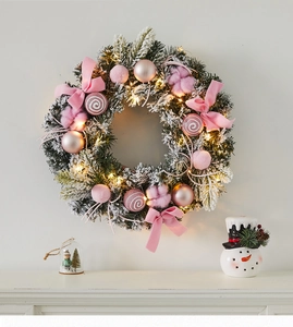 Détail d'une couronne de Noël rose avec lumières LED chaudes et ornements décoratifs