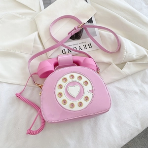 Detail of pink retro telephone crossbody bag with glossy finish and dial design
