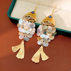 Detailed macro view of vintage golden fish-shaped earrings with iridescent shell scales