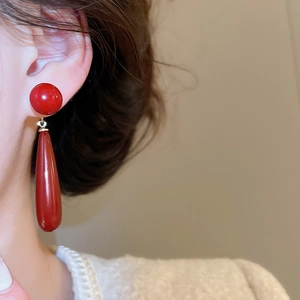 Detail of elegant red pearl teardrop earrings on model with gold hardware accents