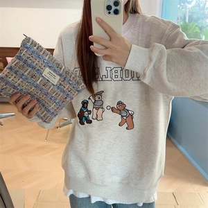 Mirror selfie showing the tweed makeup bag held with a casual beige printed sweatshirt