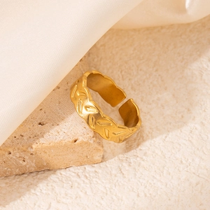 Gros plan d'une bague dorée ajustable avec motifs à chevrons sur une pierre texturée