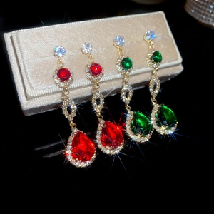 Detailed close-up of teardrop pendant earrings with red and green crystals on velvet box