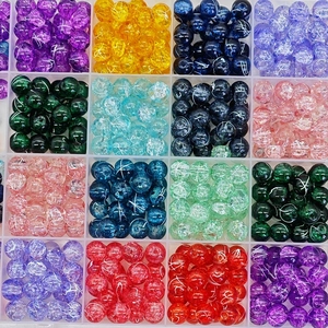 Macro view of assorted cracked glass beads sorted by color in a clear grid storage box