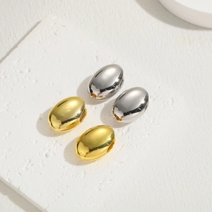 Detailed view of polished oval hoop earrings in gold and silver finishes on display