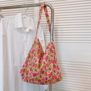 Primer plano de un bolso de algodón con estampado de tulipanes rosas en un perchero.